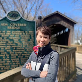 Hui-Fen smiling beside a historic covered bridge